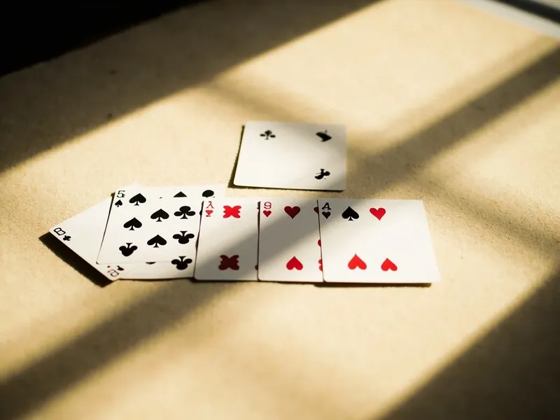An overhead view of a finished rummy meld on light felt, showing one pure sequence, one impure sequence with a joker, and one set of three-of-a-kind.